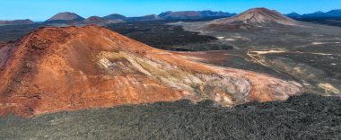 Kızıl kayalık bir dağ ve siyah volkanik toprak, lav oluşumları ve dağlık çöl manzarası ve Kanarya Adaları 'ndaki Lanzarote adaları volkanları üzerindeki insansız hava aracının çarpıcı görüntüsü..