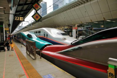 TOHOKU, JAPAN - APR 2018: Shinkansen serisi E5 HAYABUSA (yeşil) Sendai istasyonundaki E6 KOMASHI (kırmızı) serisiyle bağlantılı, arka planda 7.