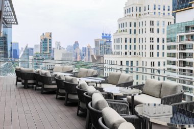 Bir gökdelenin tepesinde rahat bir oturma alanı, çatı katı bar ve restoran alanında güzel şehir manzarası olan servis alanı.