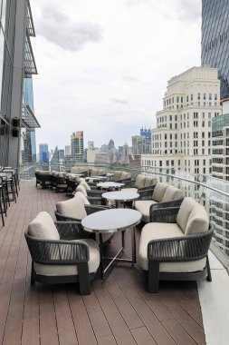 Bir gökdelenin tepesinde rahat bir oturma alanı, çatı katı bar ve restoran alanında güzel şehir manzarası olan servis alanı.