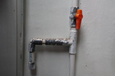 Beyaz bir duvara bağlanmış garip bir boru hattı.