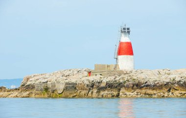 Issız adadaki eski Muglins Deniz feneri Mavi bulutlu gökyüzünün arkaplanı.
