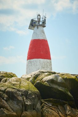 Issız adadaki eski Muglins Deniz feneri Mavi bulutlu gökyüzünün arkaplanı.