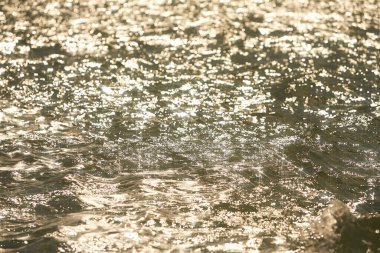 Parlak denize yansıyan güneş ışığının ayrıntıları. Suda maytap - arka plan. Güneş parlayan ve dalgalanan deniz suyu. Güçlü ve barışçıl doğa kavramı.