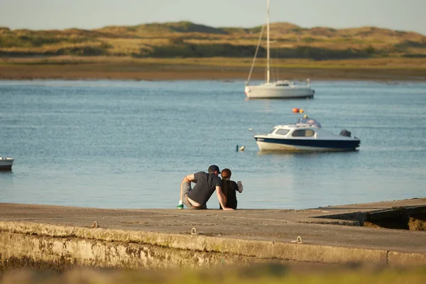 新婚旅行のカップル 恋人たちは桟橋に座って海を見ている 後ろからカップルのロマンチックなシルエット 日没時間 — ストック写真