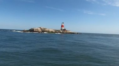 Issız adadaki eski Muglins Deniz feneri Mavi bulutlu gökyüzünün arkaplanı.