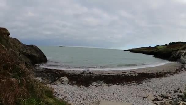 多云的天气里 美丽的岩石海滩上闪耀着蔚蓝的爱尔兰海浪 — 图库视频影像