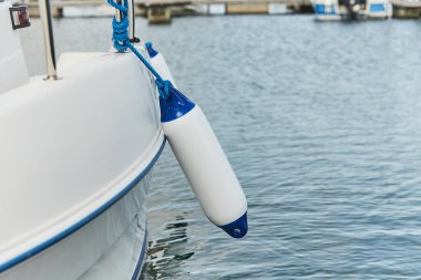 Korunmak için tekne ile rıhtım arasında asılı beyaz çamurluklar. Deniz çamurlukları