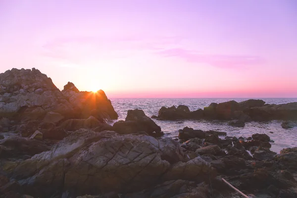 Rocher sur la plage avec coucher de soleil violet — Photo