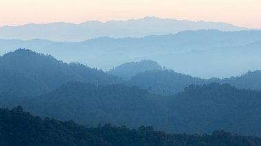 Güneş doğarken tropikal yağmur ormanlarının puslu mavi dağ sırasının doğal manzarası.