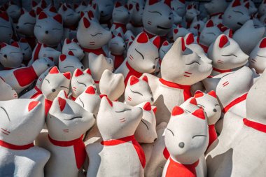 Beyaz ve kırmızı renkli tilki bebeklerine yakından odaklan. Gülümse ve gözlerini kapat. Tapınağın içindeki güneş ışığına dokun..