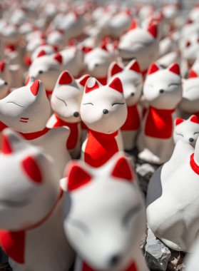 Beyaz ve kırmızı renkli tilki bebeklerine yakından odaklan. Gülümse ve gözlerini kapat. Tapınağın içindeki güneş ışığına dokun..