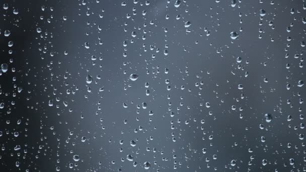 Gotas de agua de nieve derretida y copos de nieve raros en vidrio de ventana sobre fondo gris — Vídeos de Stock