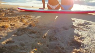 Sörfçü kızlar okyanus plaj günbatımı bakıyor.