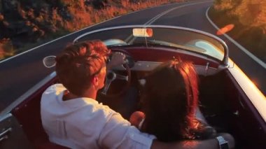 Mutlu çift klasik Cabrio araba sürüş gün batımına doğru ülke yolda