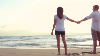 Güzel genç çift Beach günbatımında elele