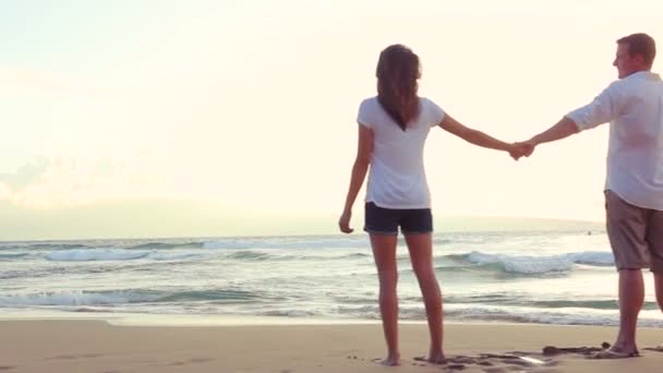 Beautiful Young Couple Holding Hands at Beach Sunset