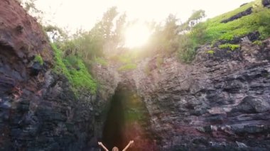 Young Attractive Woman Standing On Sea Cliff Looking Up at Sun Amazing View. Victory Pose Arms Up