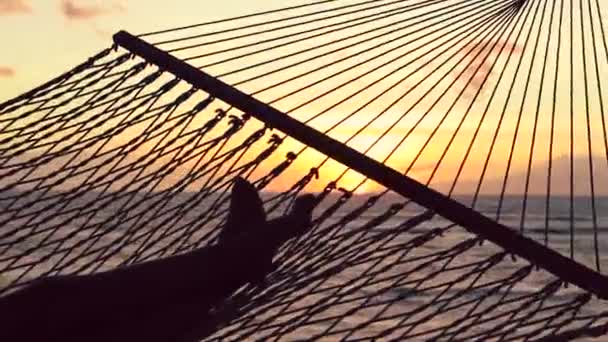 Pies balanceándose en una hamaca por el Océano Entre al atardecer. Cálido tono de color de Instagram — Vídeos de Stock