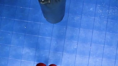 Young Strong Female Athlete Punching Body Bag Shot From Above Looking Down. Self Defense Training.
