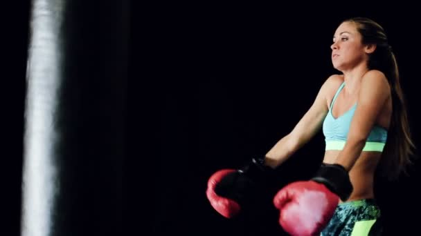 Hermosa fuerte joven boxeador entrenamiento con guantes rojos en bolsa de cuerpo negro — Vídeos de Stock