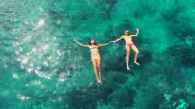 Kristal mavi okyanusta yüzen bikinili güzel kadınlar. Lüks tatil yaşam tarzı.