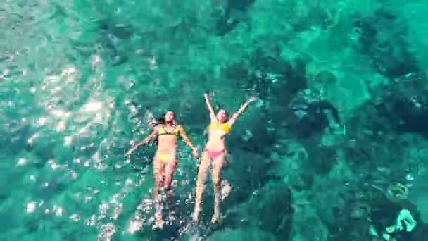 Belles femmes en bikinis flottant dans l'océan bleu cristal. Style de vie de vacances de luxe . — Video