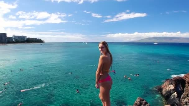 Krásná dívka skáče z útesu do oceánu v bikinách na Havaji. — Stock video