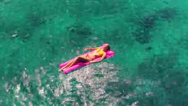 Vackra unga blonda kvinnor i Bikini svävar på rosa uppblåsbar flotte i kristall hav i Hawaii. — Stockvideo