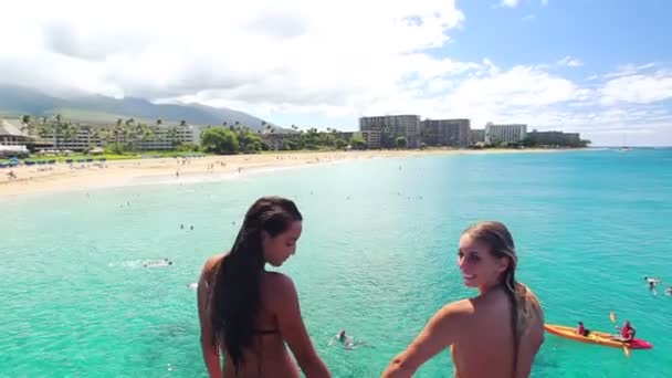 İki kız arkadaş elele bikinis Hawaii okyanusa uçurumdan atlamak. — Stok video