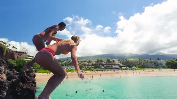 İki kız arkadaş Bikinis Hawaii okyanusta içine uçurumdan atlamak. — Stok video