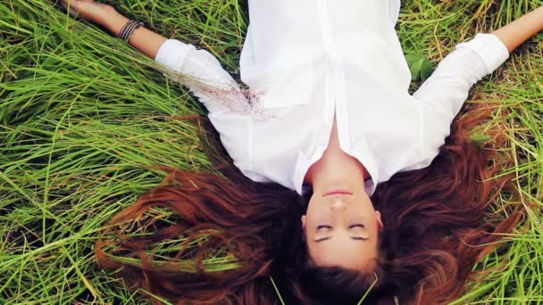 美丽的女孩躺在草地上和梦想。享受大自然。眼睛闭合放松 — 图库视频影像