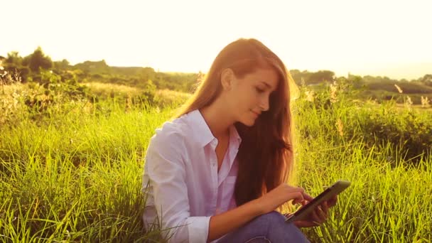 Mujer joven usando la pantalla táctil de la computadora de la tableta. Hermosa luz del atardecer al aire libre en la naturaleza . — Vídeos de Stock