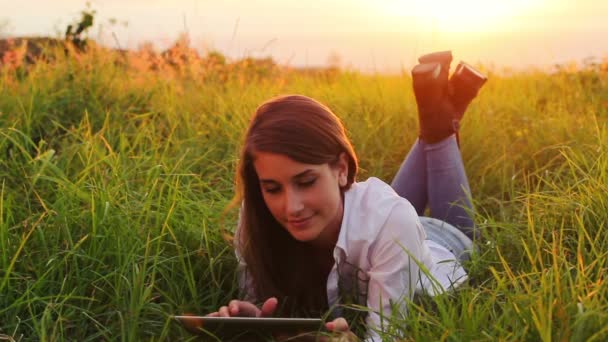 Mujer joven usando Tablet PC pantalla táctil al aire libre en la naturaleza. Hermosa luz puesta del sol . — Vídeo de stock