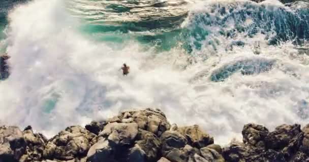 海の崖から夕日に飛び降りる若者の4k空中ショット. — ストック動画