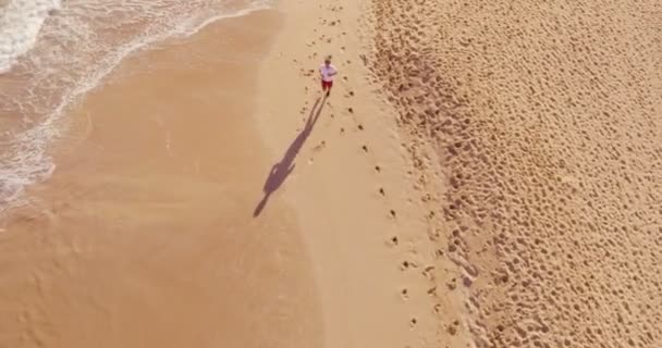 4k空中ランニングランナー男性アスリートトレーニング屋外日の出時にビーチで運動 — ストック動画