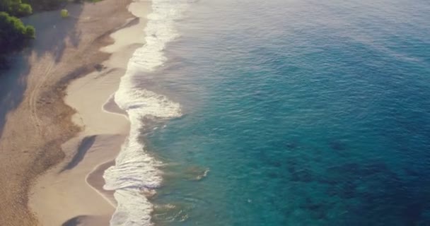 4k lucht vlucht over wit zandstrand en prachtige blauwe oceaan. Geweldige zonsopgang boven tropisch landschap. — Stockvideo