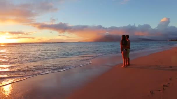 Smekmånad ungt romantiskt par kysser på stranden njuter av solnedgången — Stockvideo