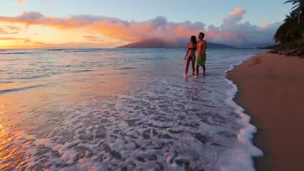Feliz pareja romántica joven caminando en la playa disfrutando de la puesta de sol — Vídeo de stock