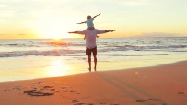 Baba ve oğul birlikte gün batımında sahilde kaldırdı uçak silah oyun.