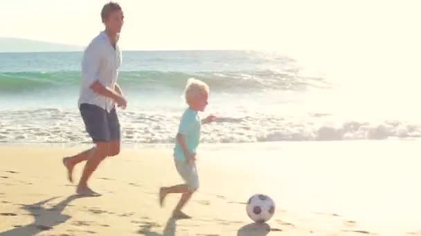 Ojciec i syn razem gra piłka nożna na plaży o zachodzie słońca. — Wideo stockowe