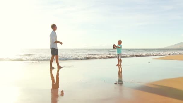 Ojciec i syn razem rzucanie piłki nożnej na plaży o zachodzie słońca. — Wideo stockowe