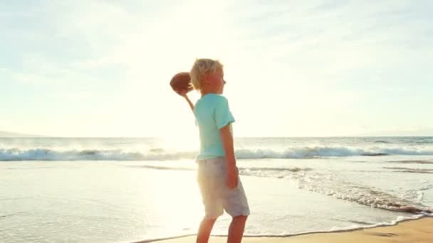 Młody chłopak gra piłka nożna na plaży o zachodzie słońca. — Wideo stockowe