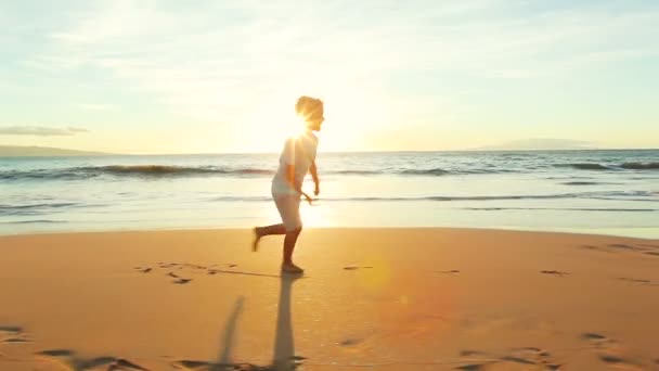 Młody chłopiec działa dla zabawy w ramiona ojców na plaży o zachodzie słońca. — Wideo stockowe