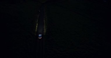4 k araç tepeler ülkede yol virajlı gece sürüş. Havadan görünümü. Farlar.