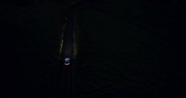 4 k araç tepeler ülkede yol virajlı gece sürüş. Havadan görünümü. Farlar.