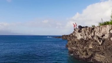 Mavi okyanus içine atlama havadan görünümü Cliff. Genç adam ağır çekimde uçurumdan atlar. Yaz Extreme spor.
