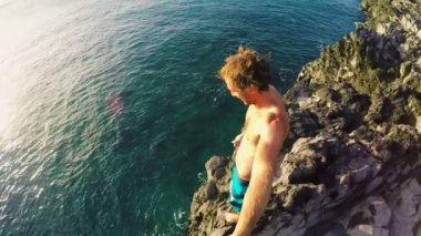POV ağır çekim günbatımı Jumping Cliff. Okyanus içine uçurumdan atlamak atletik genç adam.