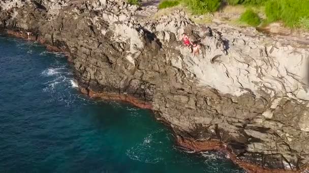 Letecký pohled na útesu do modré moře. Mladý muž skočí z útesu v pomalém pohybu. Letní Extreme Sports. — Stock video
