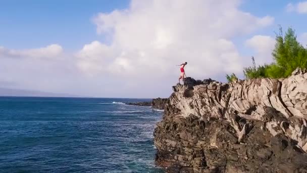 Vzdušné zobrazení Cliff skáčou do modrého oceánu. Letní akční životní styl. Mladý muž skáče ze skály v pomalém pohybu. — Stock video